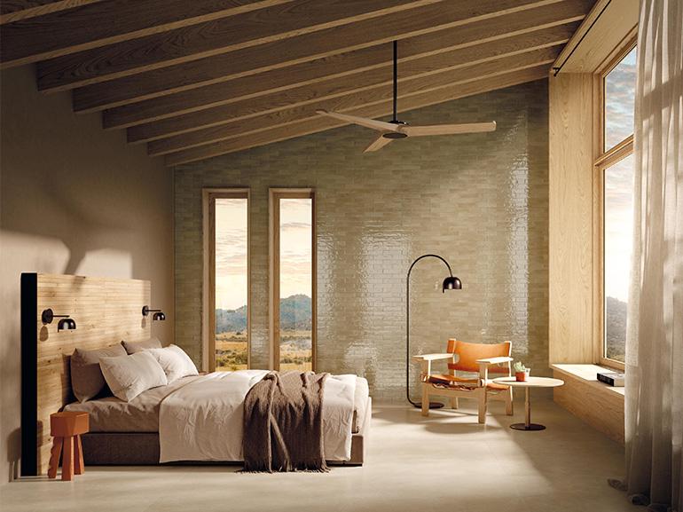 Nell’immagine, elegante camera da letto realizzata con GLIM, una collezione vitaminica capace di decorare gli ambienti con il colore, grazie a brick smaltati dal finish brillante. A parete, nel formato 6x24cm, la finitura Tortora, colore classico e moderno al contempo, capace di donare un tocco di raffinatezza e grande personalità agli interni. A pavimento Nobu, nella tonalità Beige e nel formato 120x120, il nuovo effetto pietra di FAP Ceramiche ispirato alla natura. Infine, la testata del letto è realizzat