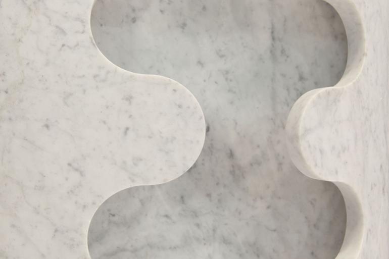 Bianco Carrara Onda -  Superficie 3D realizzata in Bianco Carrara con finitura satinata. La superficie presenta il frontale sagomato e tagliato a onde con macchina waterjet 5 assi. Finitura manuale interna ed esterna. All&rsquo;interno possono essere montati diversi elementi decorativi quali luci, specchi o creare una decorazione con piante e fiori.