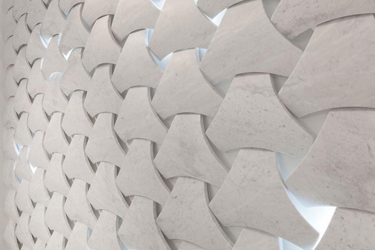 Bianco Carrara &ldquo;Scudo&rdquo; -  Questo tipo di rivestimento decorativo in Bianco Carrara con finitura satinata, &egrave; caratterizzato dalla tridimensionalit&agrave; di ogni elemento e garantisce ventilazione naturale. I vuoti e pieni possono essere integrati con elementi di verde o illuminazione tali da valorizzare la parete. La parete viene realizzata attraverso aggregazione modulare di elementi fissati meccanicamente su strutture esterne o interne dell&rsquo;edificio.